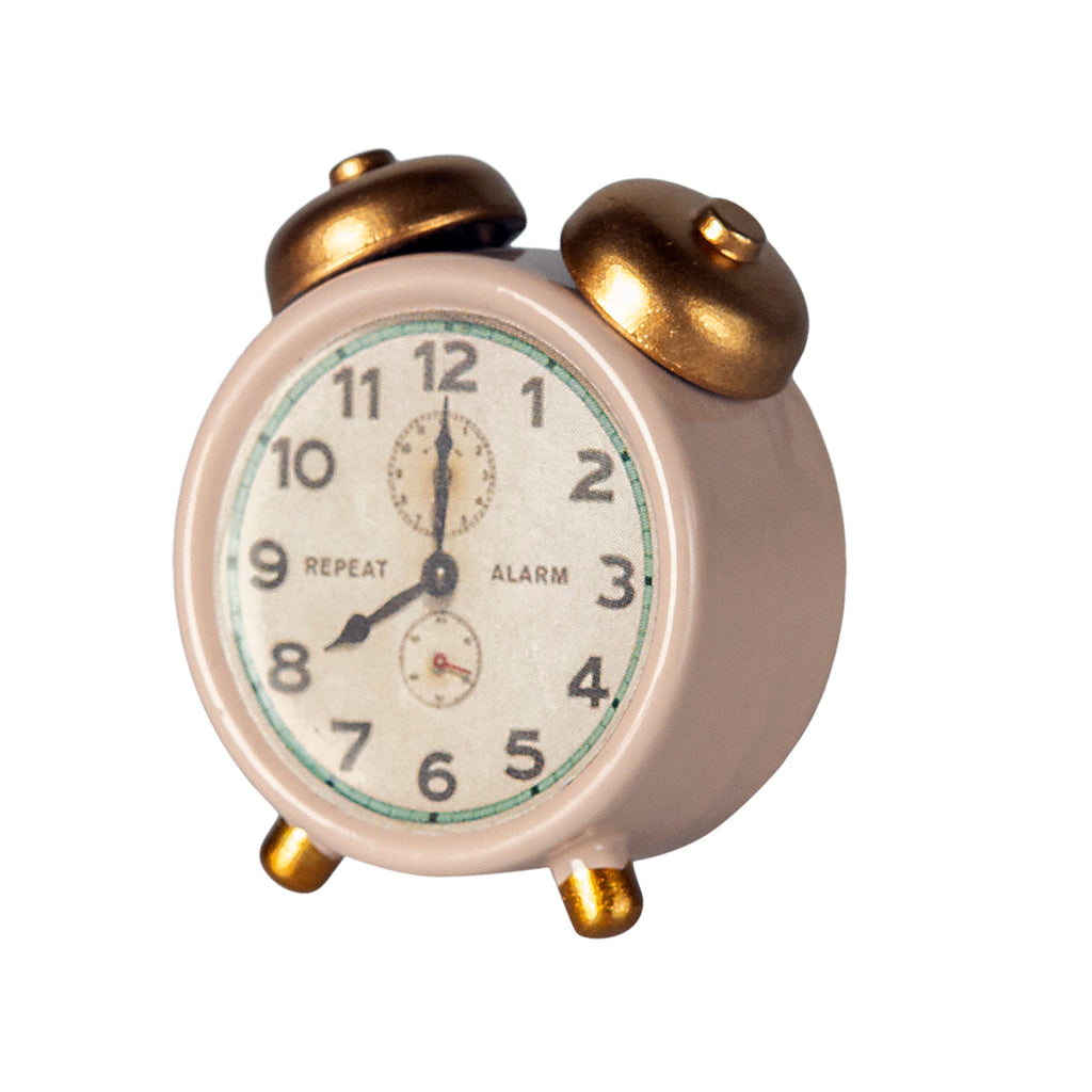 Side view of the Maileg alarm clock in powder pink with gold details on the bells and legs.