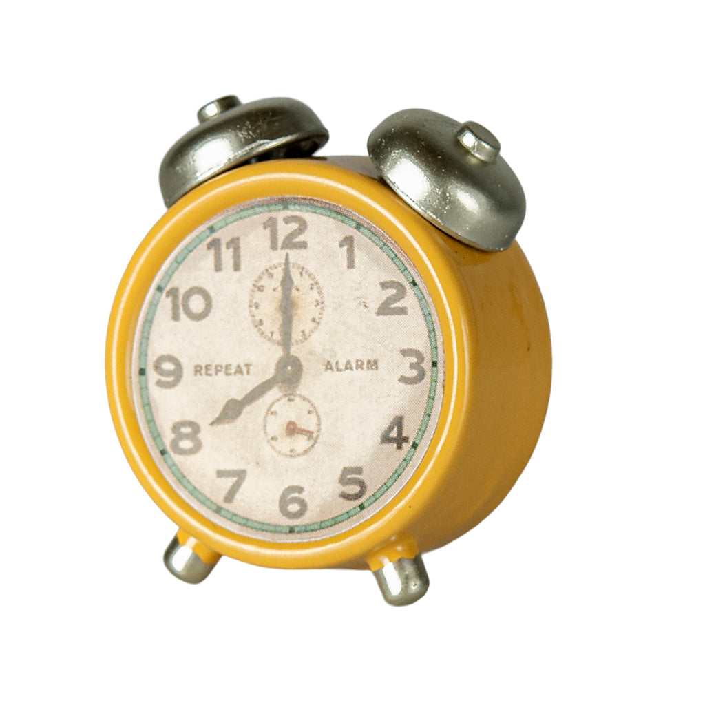 Side view of the Maileg alarm clock in yellow, featuring silver accents on the bells and legs