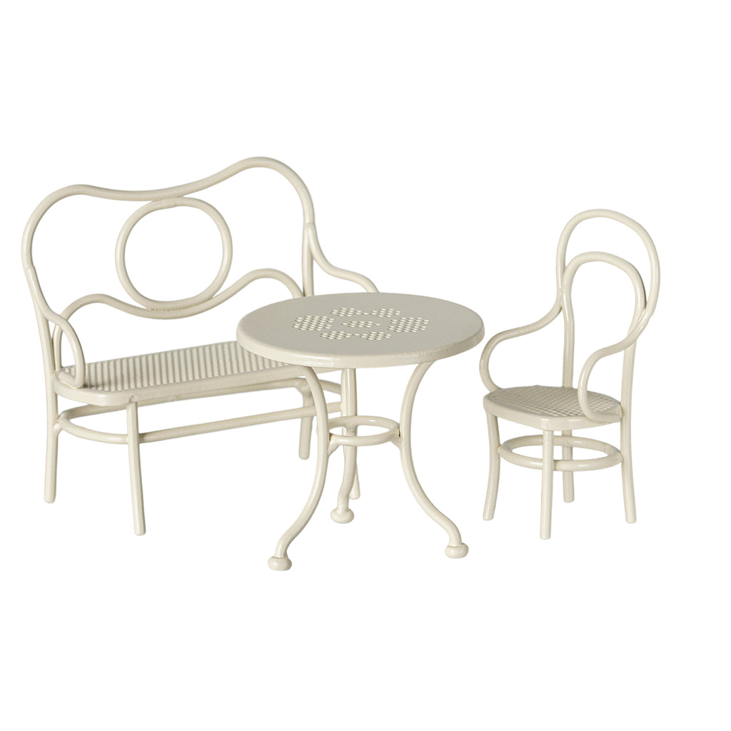 A charming Maileg café set for mice in off white, featuring a round metal table with a delicate punched flower pattern, accompanied by a matching chair and bench.