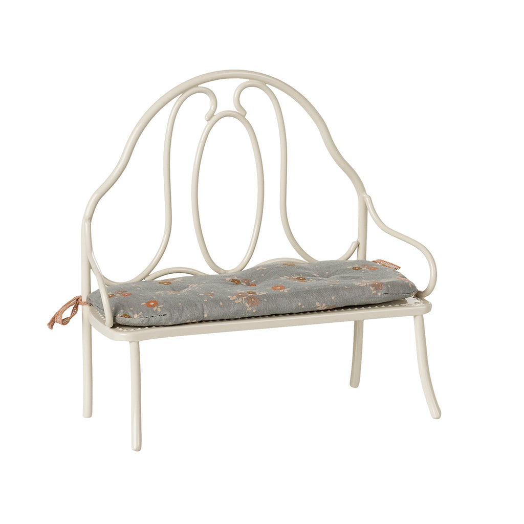 A charming Maileg vintage-style metal bench in off white, featuring a delicate blue floral-patterned cushion tied to the back poles.