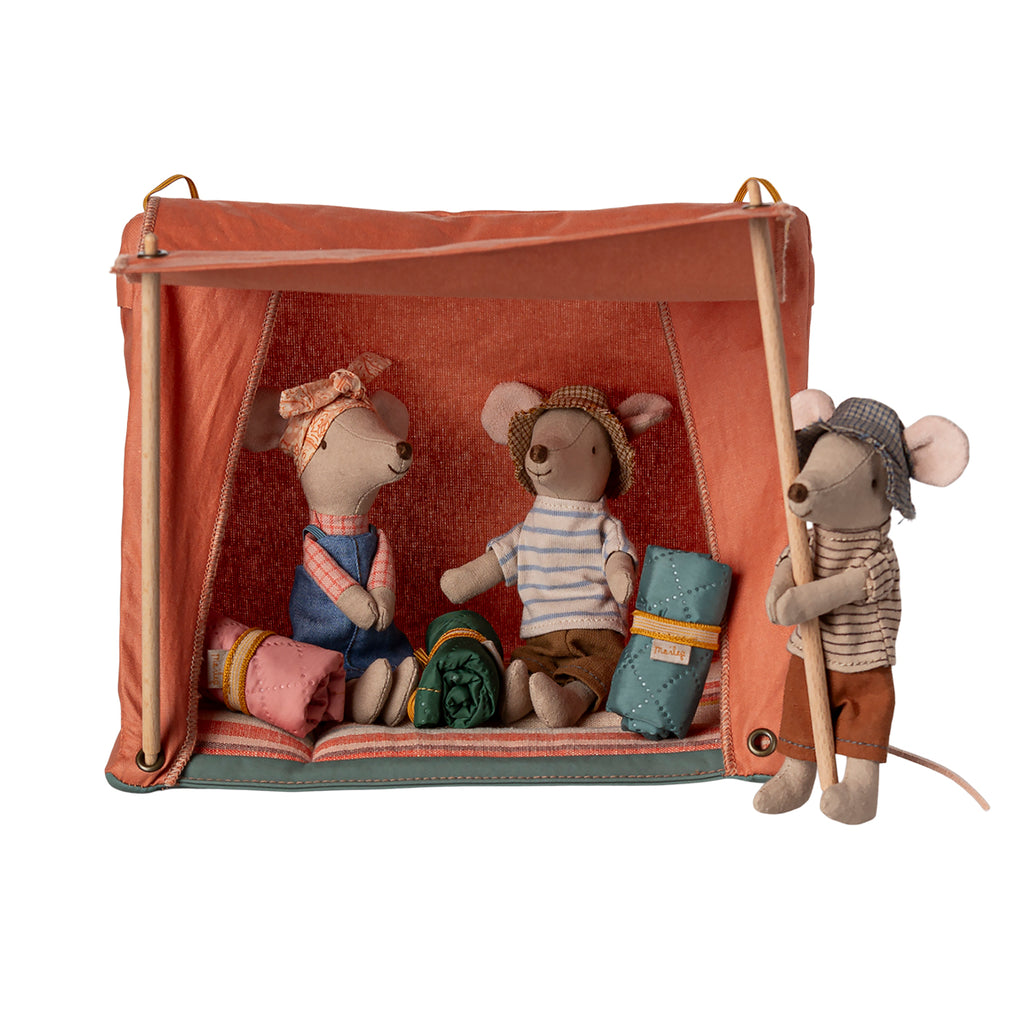 Two Maileg hiker mice are nestled inside the orange tent in their sleeping bags, while another hiker mouse playfully holds onto a tent pole.