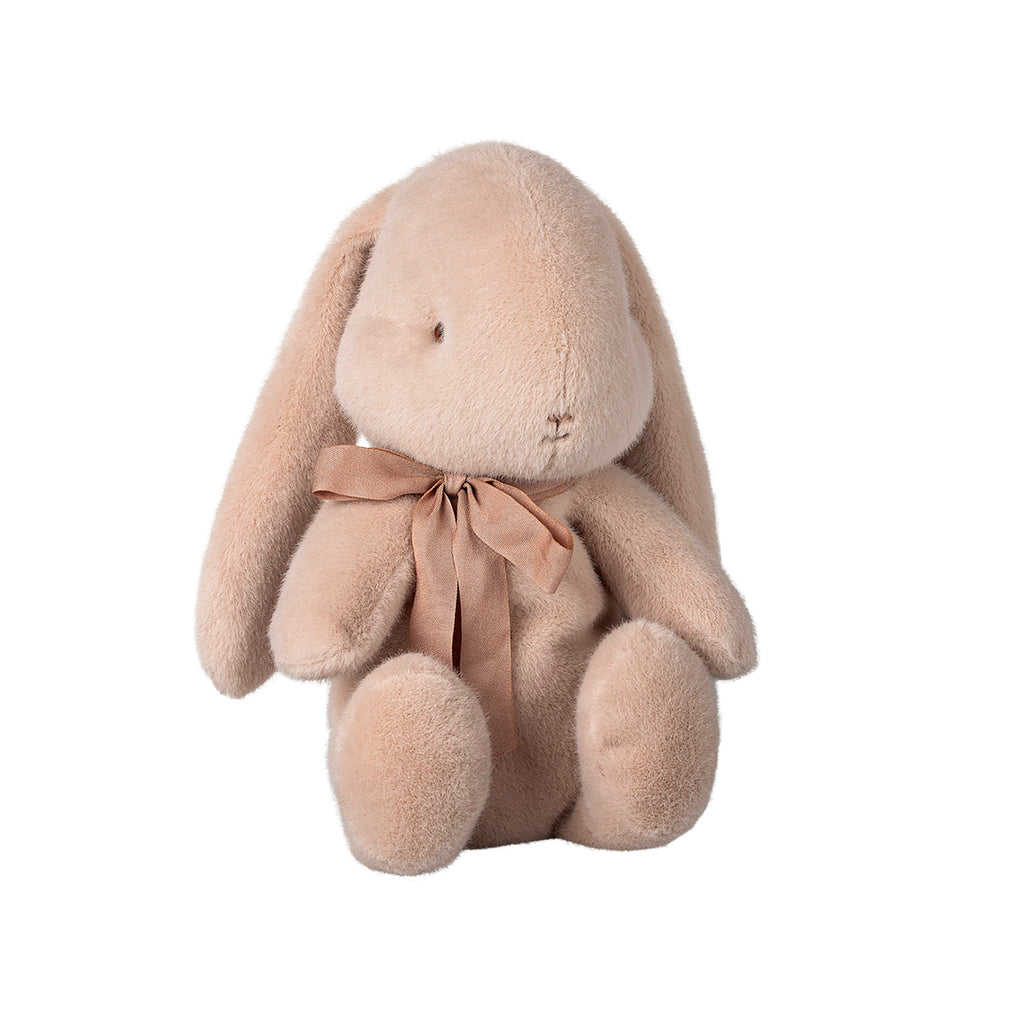 A delightful Maileg medium bunny in a soft light powder colour, sitting elegantly with a pretty pink bow tied around its neck