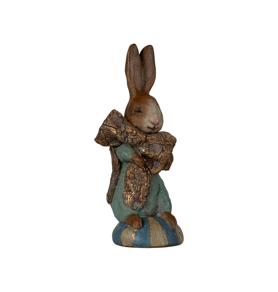 Maileg Easter Bunny figurine holding a gold-accented ribbon, standing on a striped pedestal