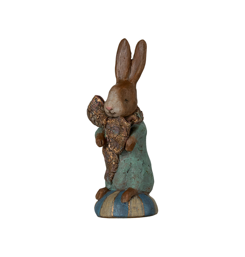 Maileg Easter Bunny figurine holding a gold-accented ribbon, standing on a striped pedestal