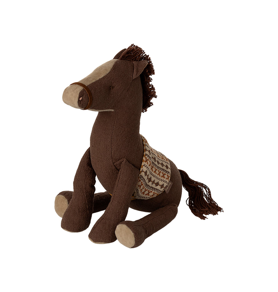 Maileg medium brown pony sitting down with a cotton string mane, tail, and a detailed knitted saddle."