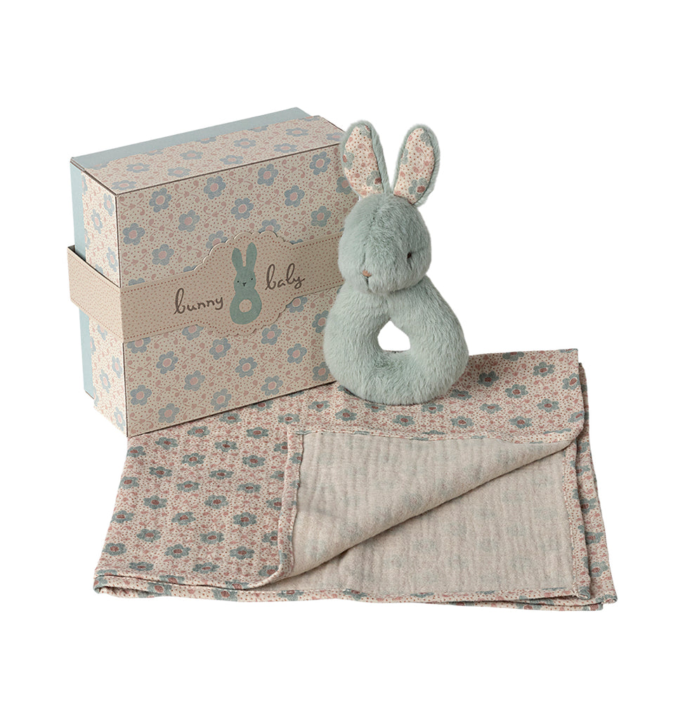 Mint Maileg rabbit rattle resting on a patterned cotton cloth, displayed next to its gift box