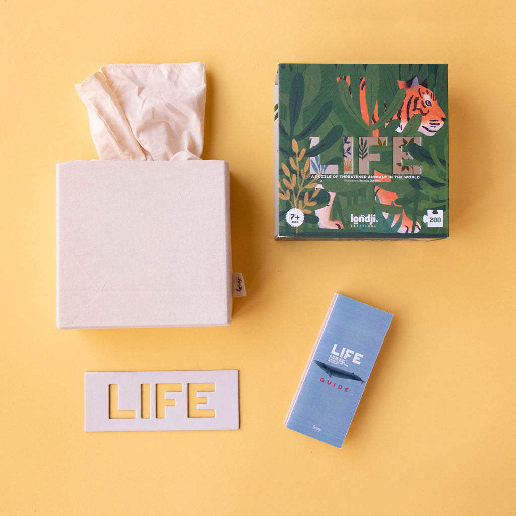 Open "LIFE" puzzle set, showing the box, a guidebook, and a fabric bag for storage.