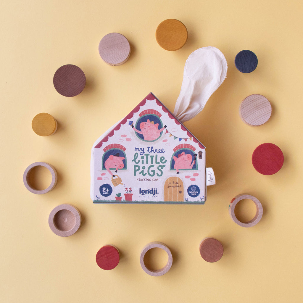 Londji My Three Little Pigs stacking game in house-shaped packaging, surrounded by colourful wooden pieces