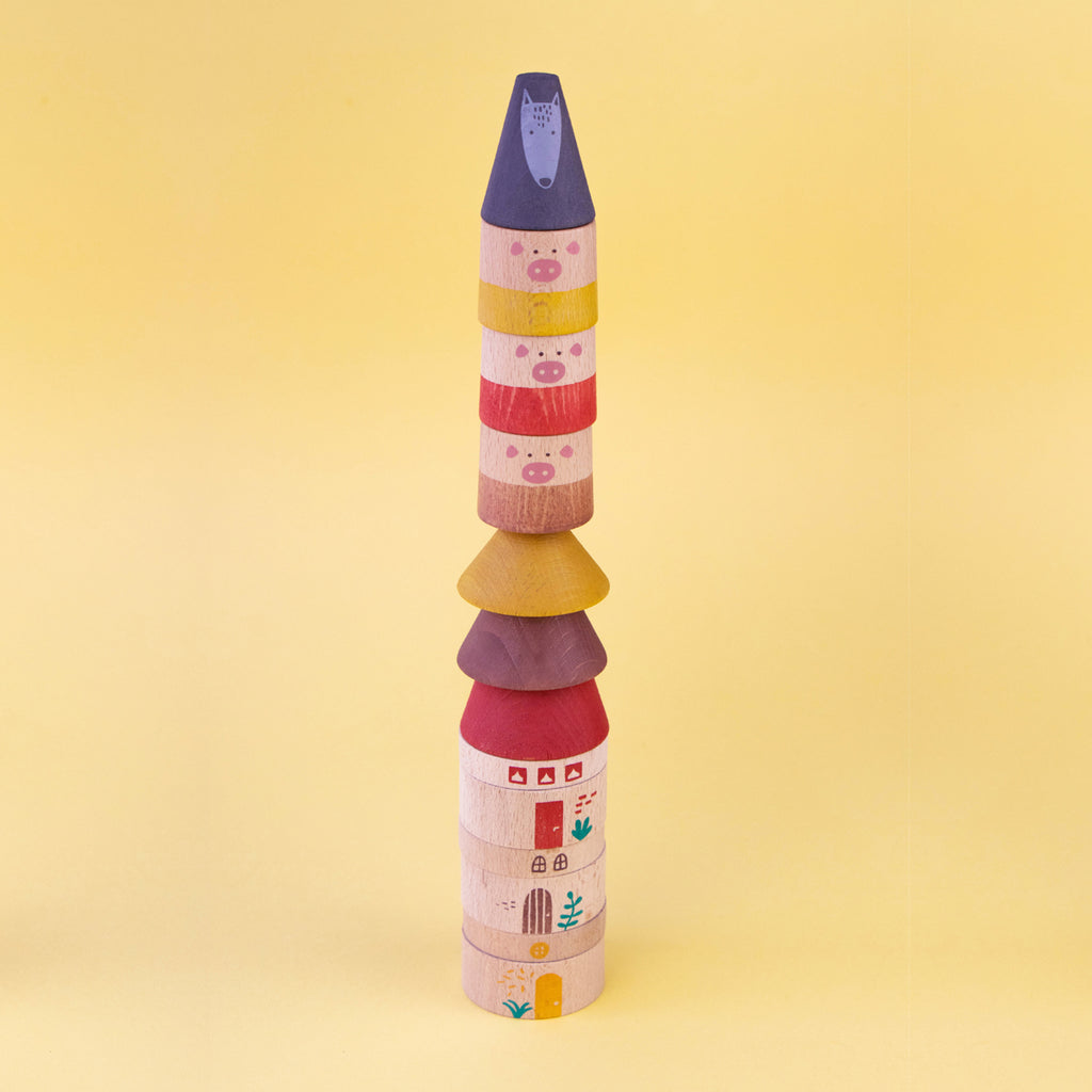 Tall tower built from wooden pig and house pieces from the Londji My Three Little Pigs stacking game.